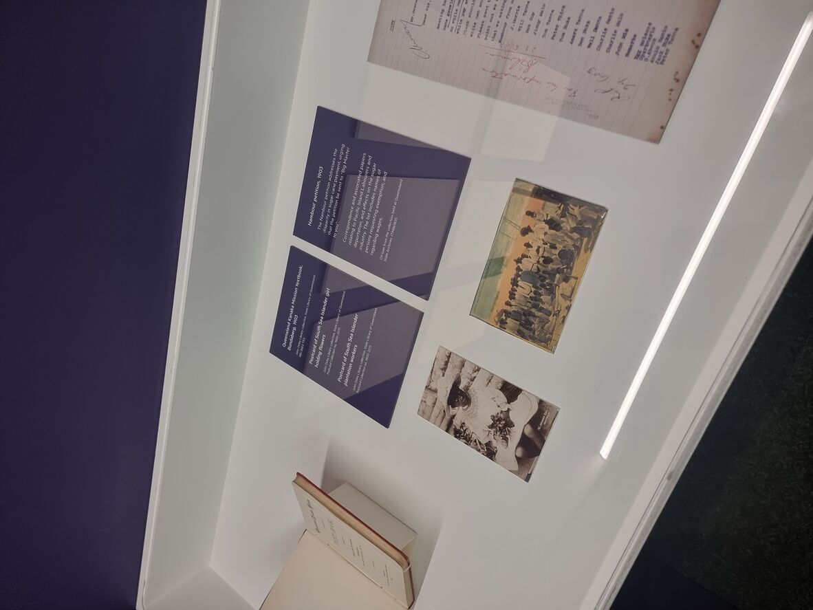 Open book, 2 postcards, typed document on display in glass case