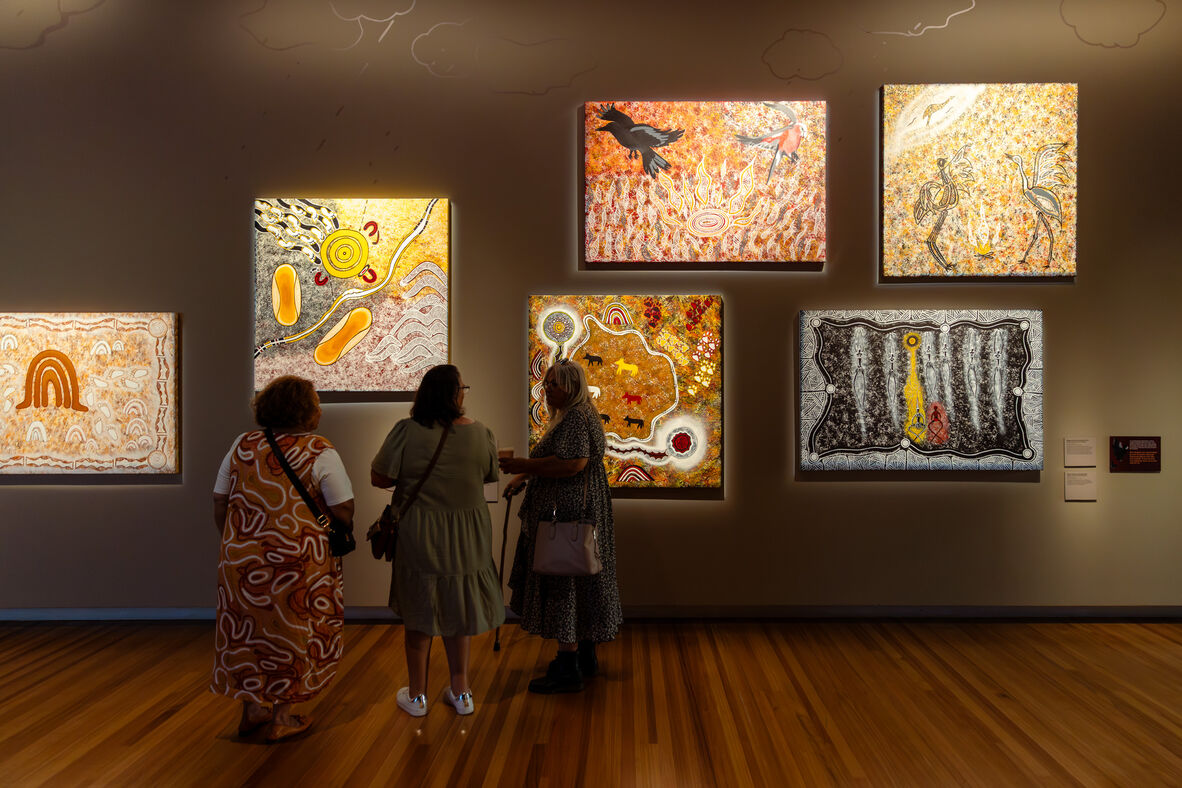 Three women viewing artwork at The unbroken spirit of the Kalkadoons exhibition, State Library of Queensland.