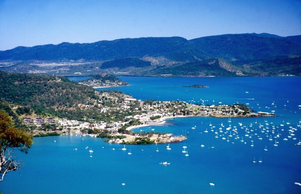 Aerial view of Airlie Beach town surrounded by blue water and sailing vessels
