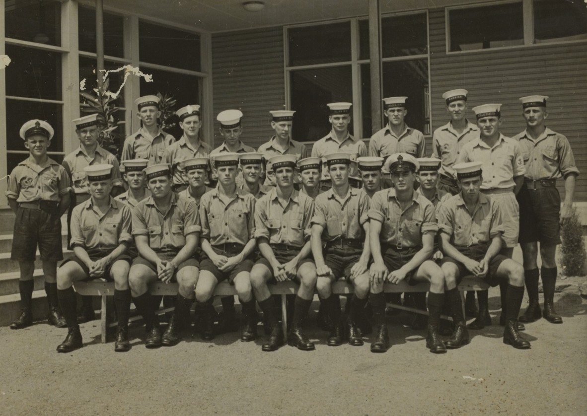 A group of navy recruits in uniform outside a building