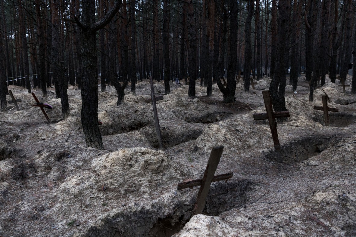 A photo of wooden crosses marking a mass burial site in snow covered woods