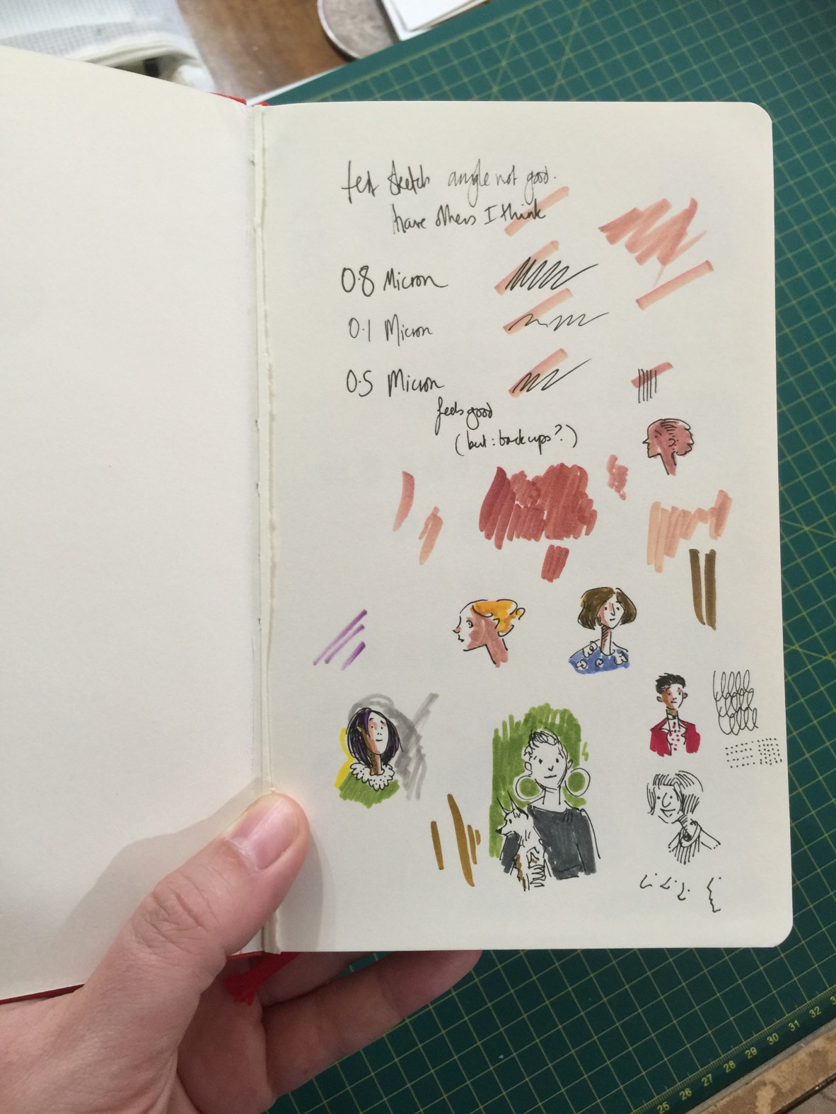 An open sketchbook filled with pen samples and sketchy portraits