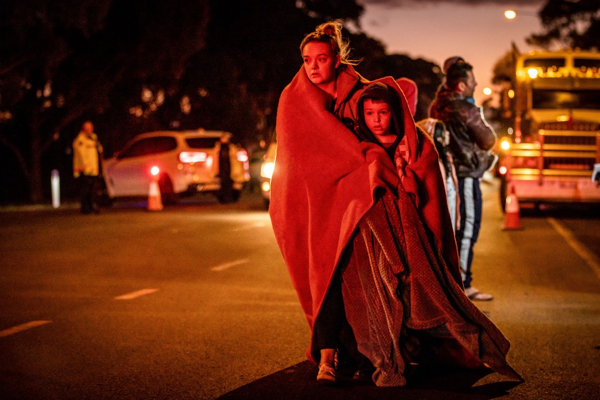 A photo of mother and her son walking away from the scene of a school bus crash both wrapped in blankets 