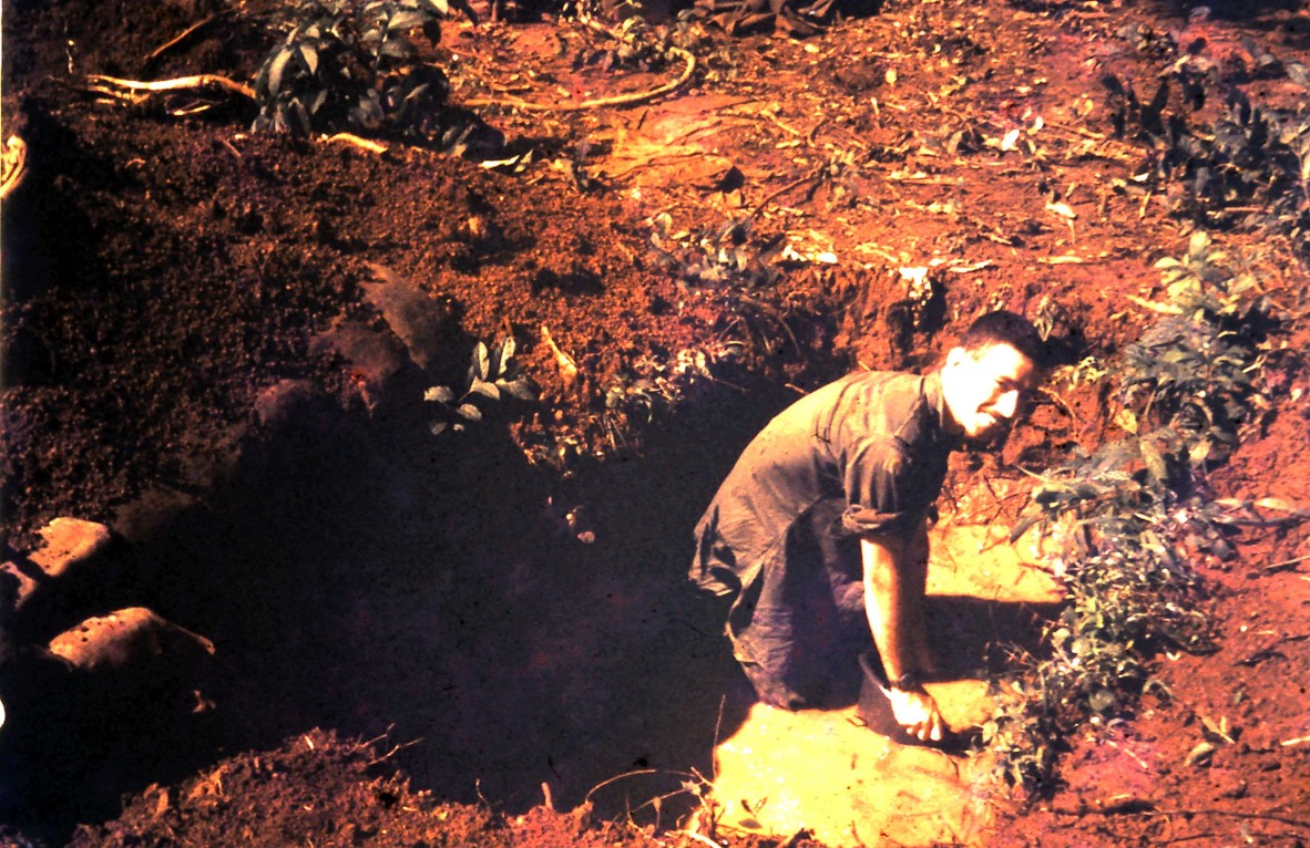 Joe bails water out of  weapons cache. Arriving in the wet season meant that the Vietnamese water table was only centimetres below the surface of the ground