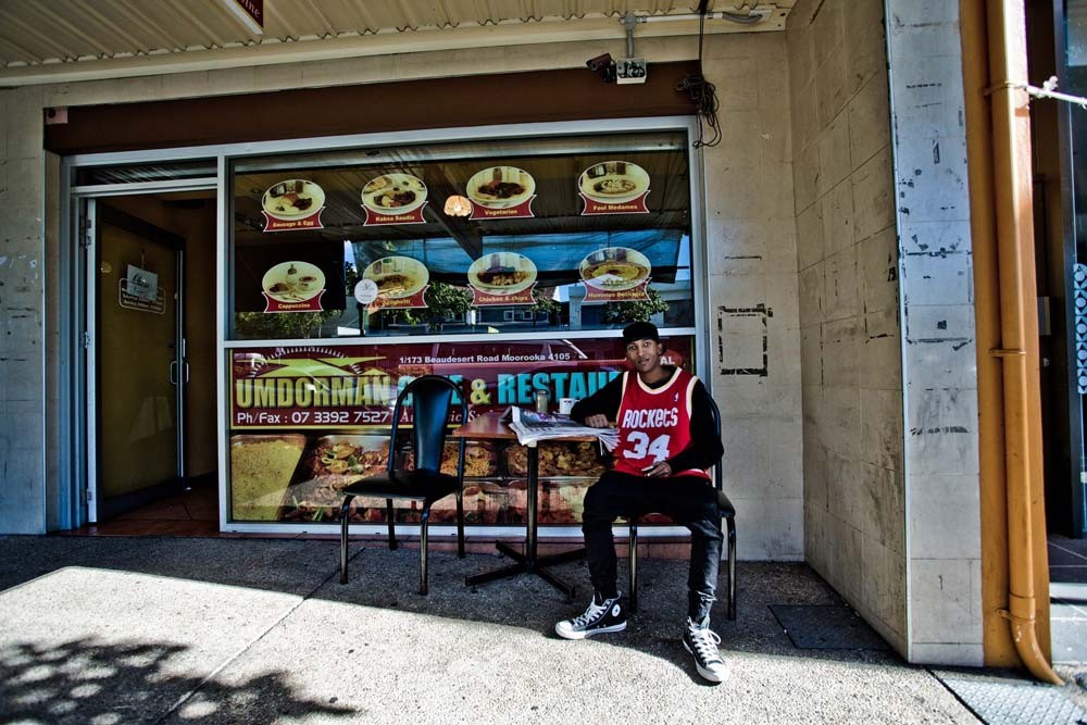 Ahmed Yusef seated at a table outside the Umdorman Cafe & Restaurant in Moorooka, Queensland, 2013. Image number  