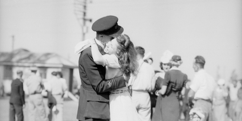 Black and white photograph of an airman in uniform embracing his girlfriend.