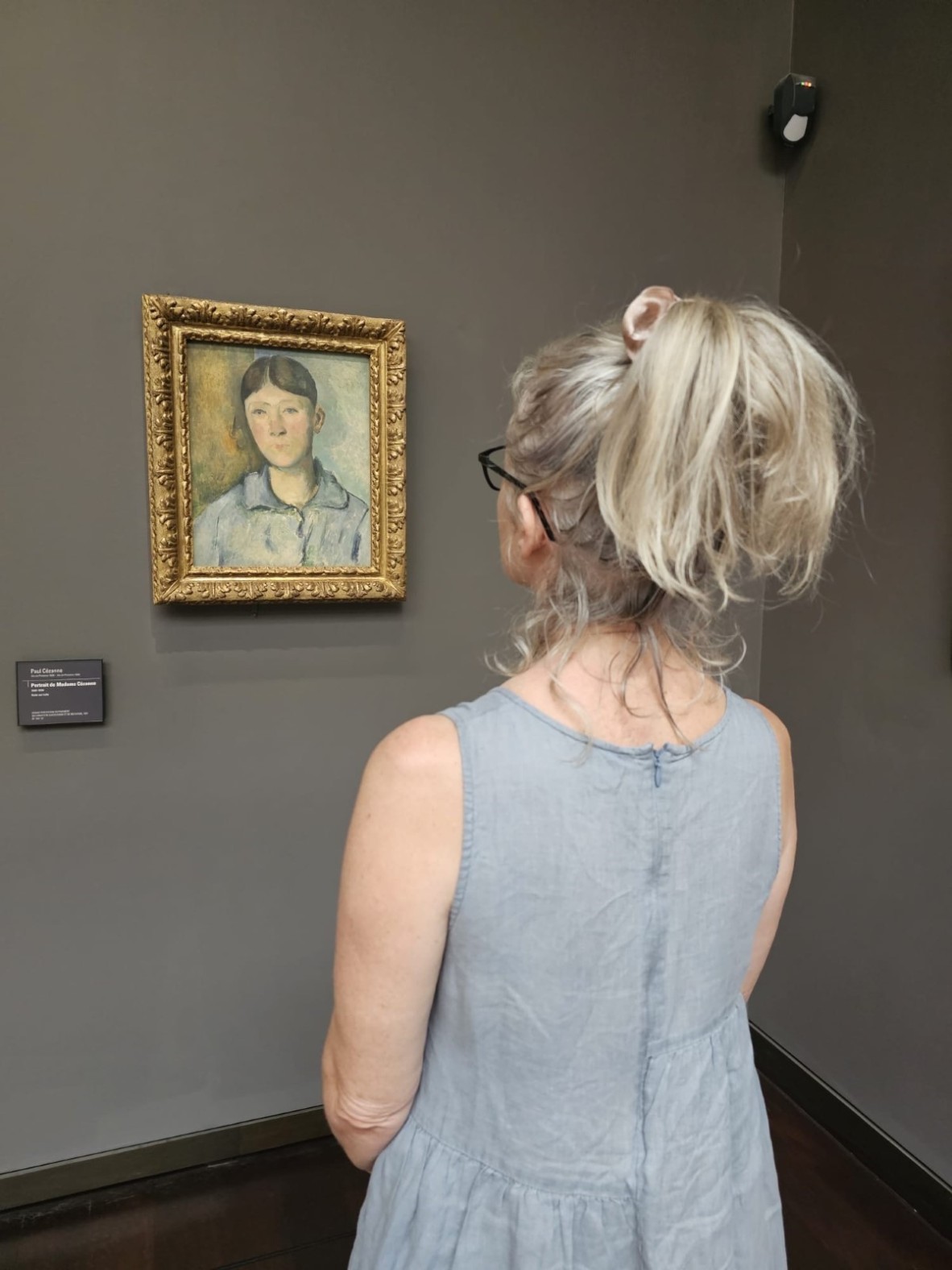 Angela O'Keeffe visiting a painting of Hortense, by Cezanne, at the Musee d'Orsay. Angela is wearing a blue-grey dress and so is Hortense.