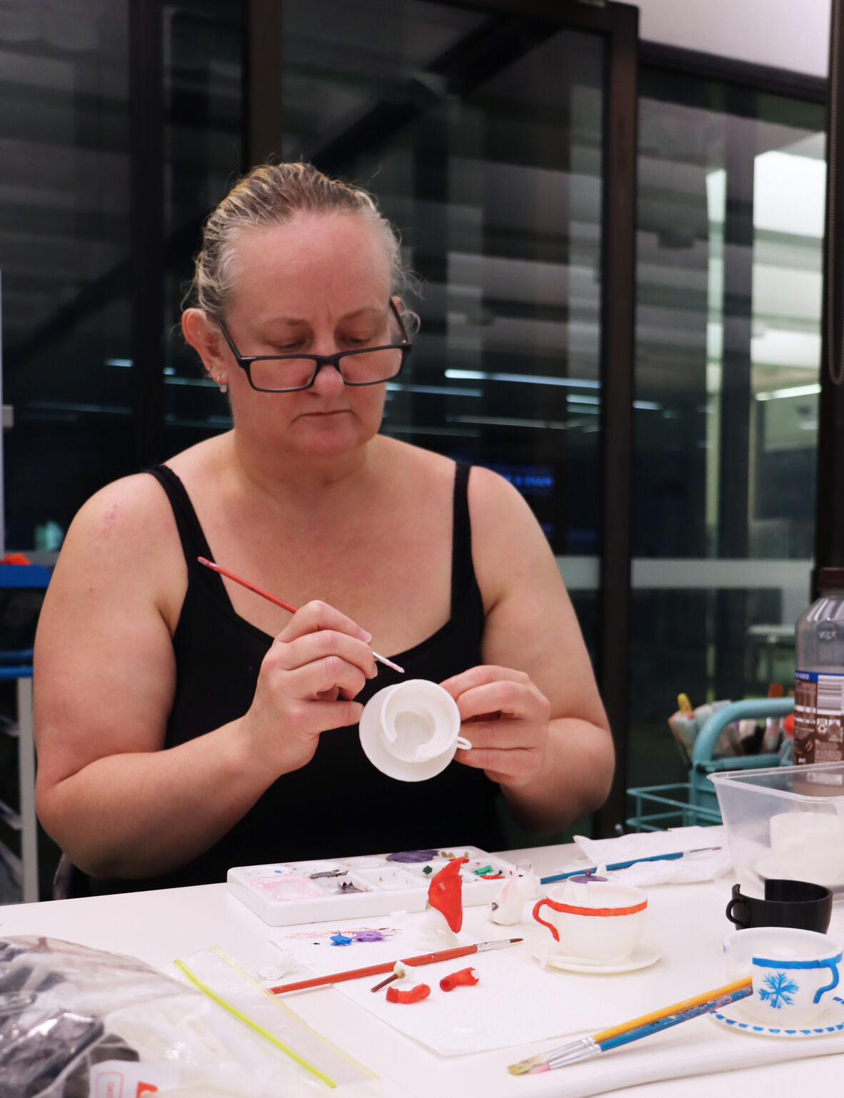 Lady hand painting a 3D printed teacup and saucer.
