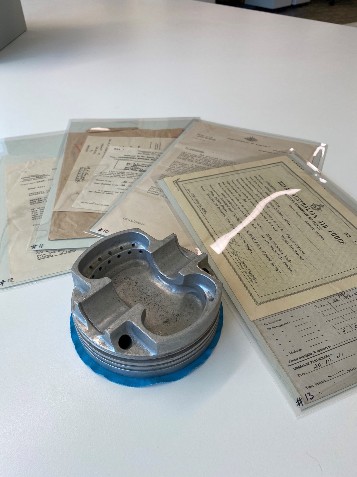 a metal ashtray made from a plane engine sits in the middle of some wartime papers. 