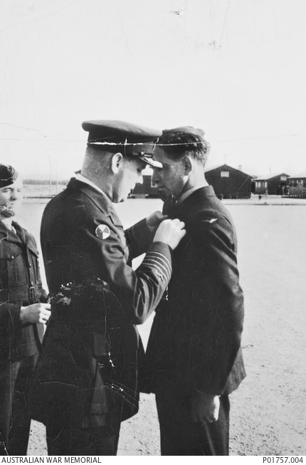 An image of three men in military uniform one is pinning an award to the collar of the other