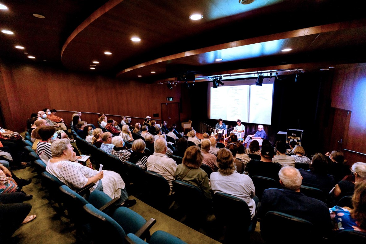 People sitting in an auditorium watching speakers on stage.