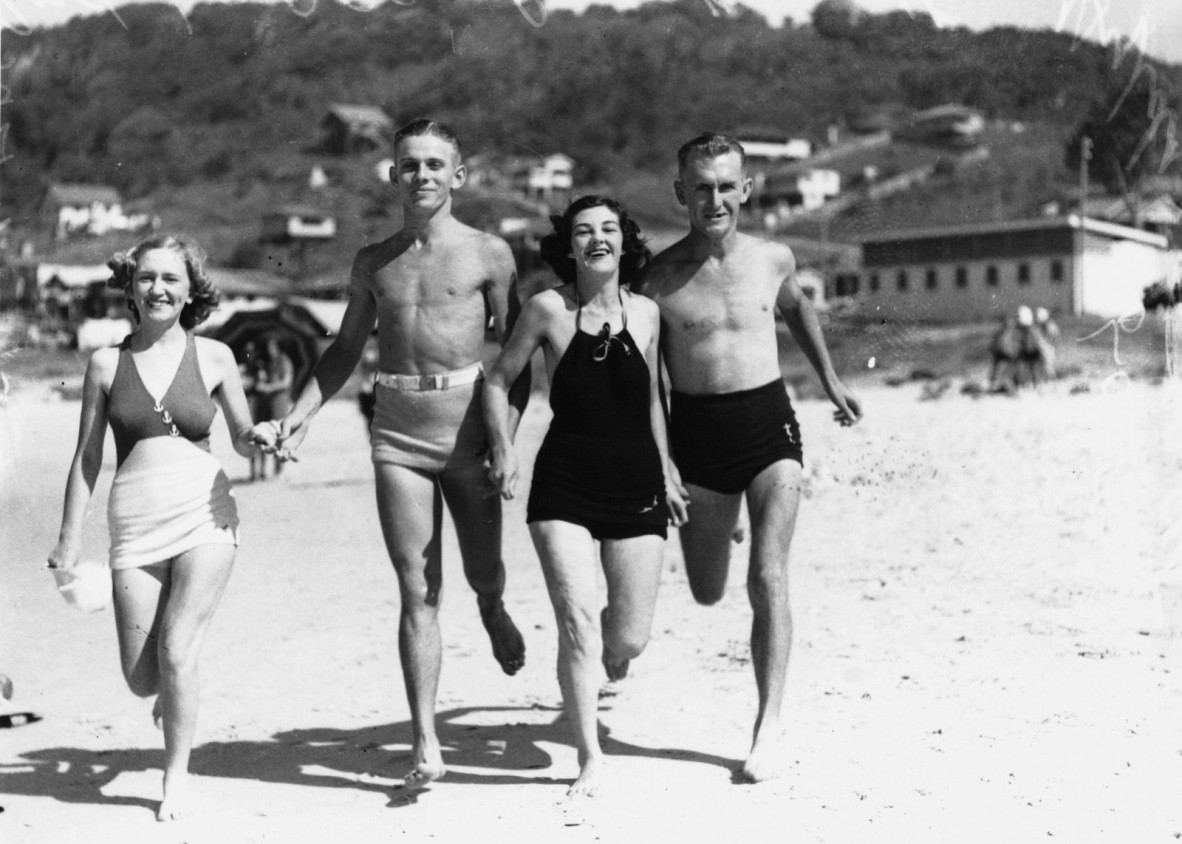 The party of beachgoers includes Mr and Mrs Roy Lores, Hylda Lores and Ron Barnett. The group runs across the sand. They wear a variety of swimwear.