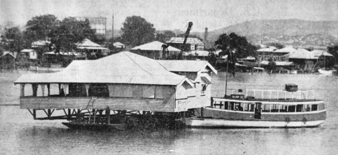 a house being moved by barge from Bulimba to Bishop Island in 1934 for Mr James Crouch. The house is passing the Gasometer at Newstead with the pilot boat guiding the punt.