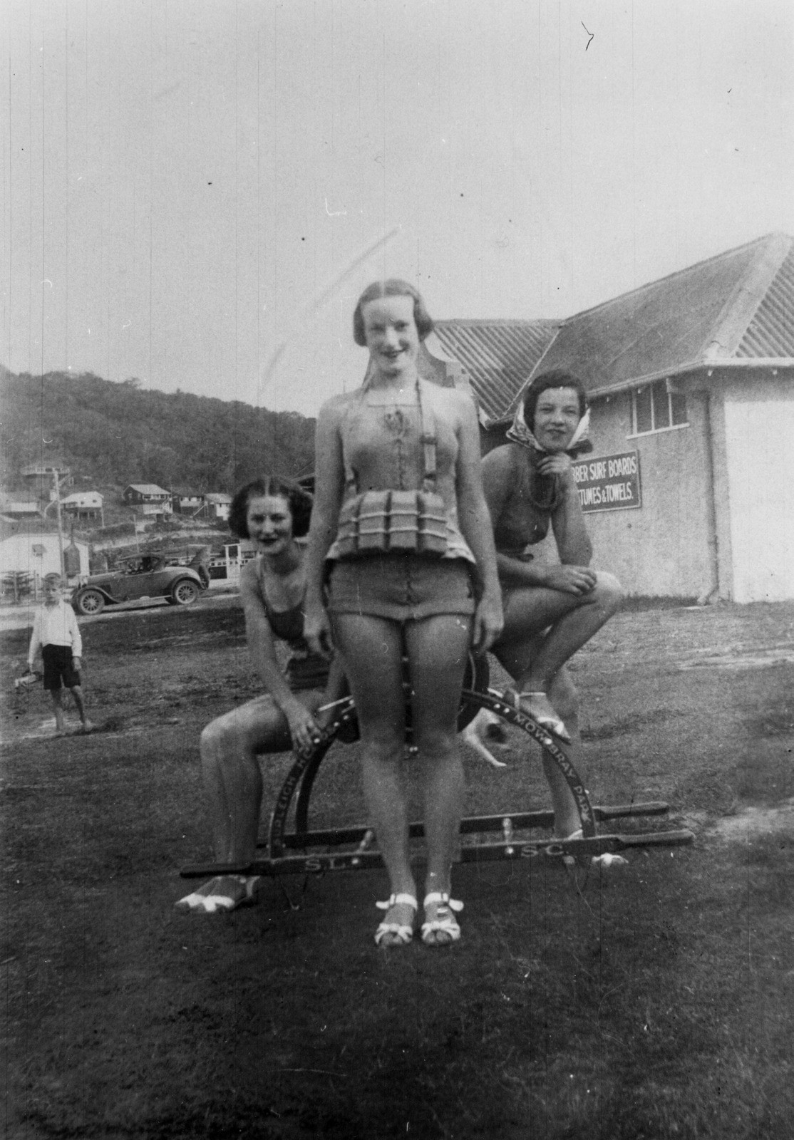 Three women posing in bathing suits with a life saving reel at Burleigh Heads surf club in 1937