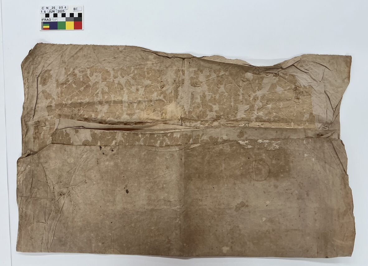 Worn, brown, creased sheet of old paper with stains and surface damage, photographed flat with a color scale in the top left