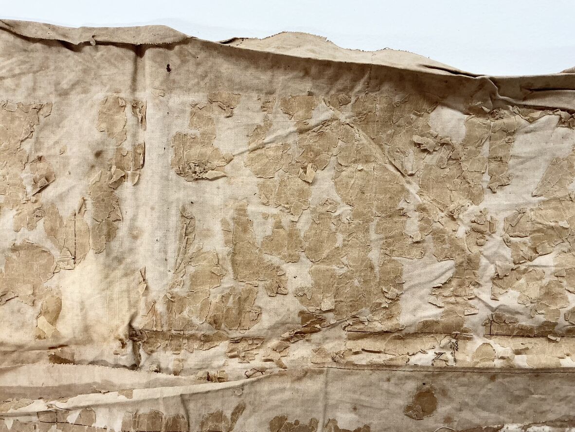 Close-up of a worn, peeling, and stained section of an old fragile map