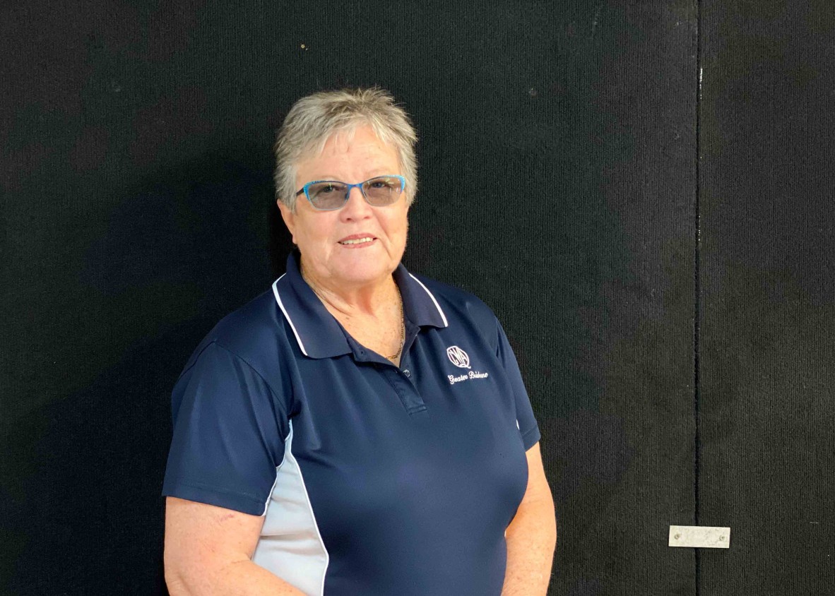 Women with short grey hair and glasses in front of black wall