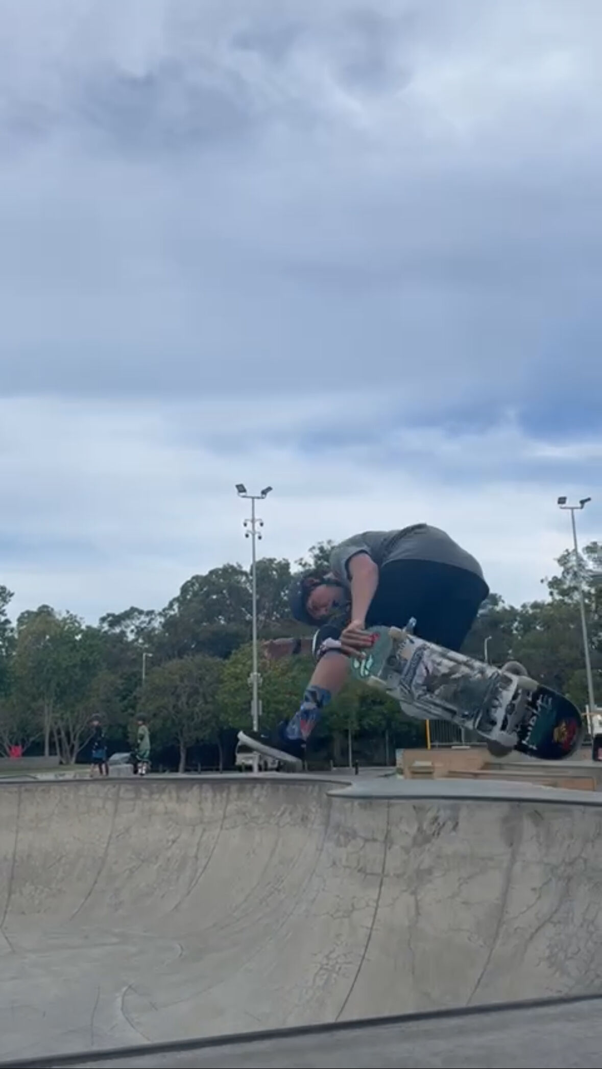 A skateboarder doing a backside judo air in the bowl at Pizzey