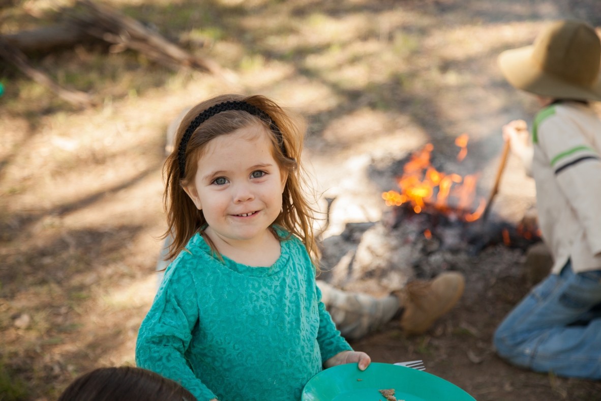 Young girl smiling with a campfire in the background