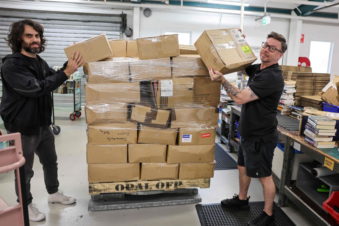 Two men unloading boxes from pallet in dispatch dock