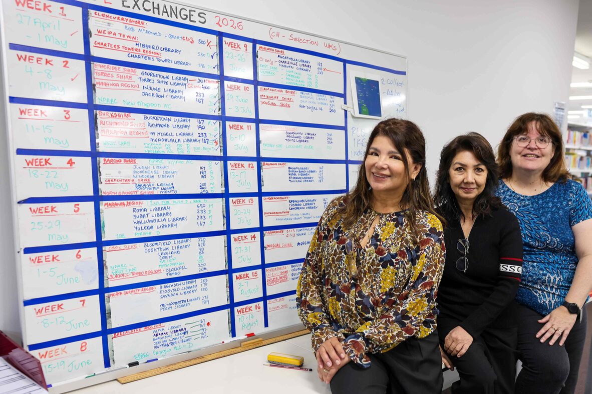 Three women sitting to the right of whiteboard titled 'Exchanges'