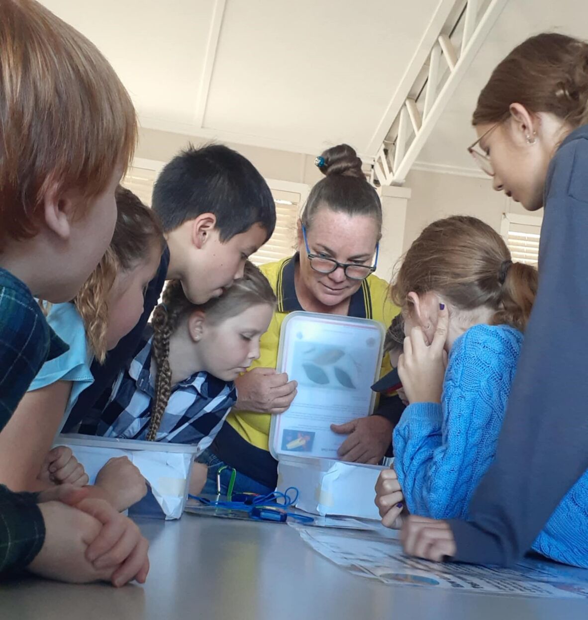 Children gather around a staff member for Discovery STEAM Workshop at Injune Library