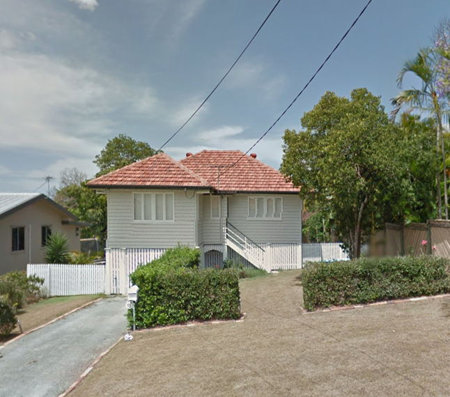 A white house with a red brick roof and tidy front garden