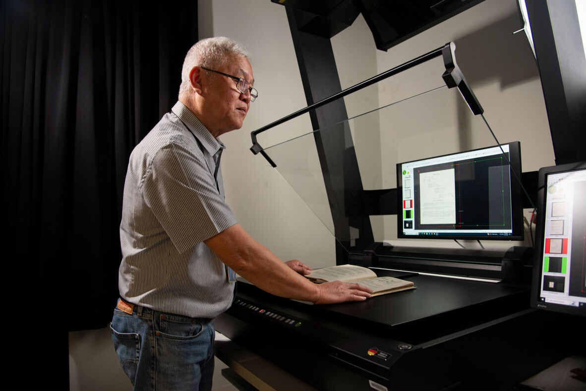Man looks at computer screen as he scans book for digitisation