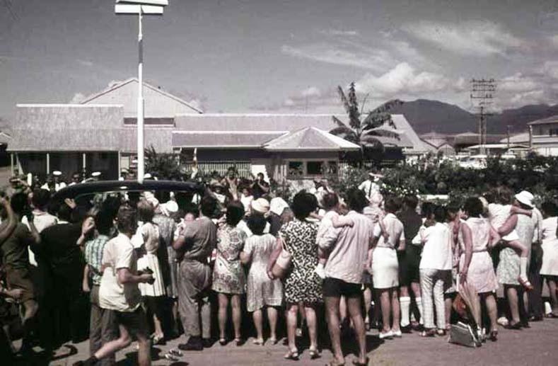 Crowd gathers around Her Majesty Queen Elizabeth II's vehicle as it leaves the Cairns wharf area, photographer A Shephard. 