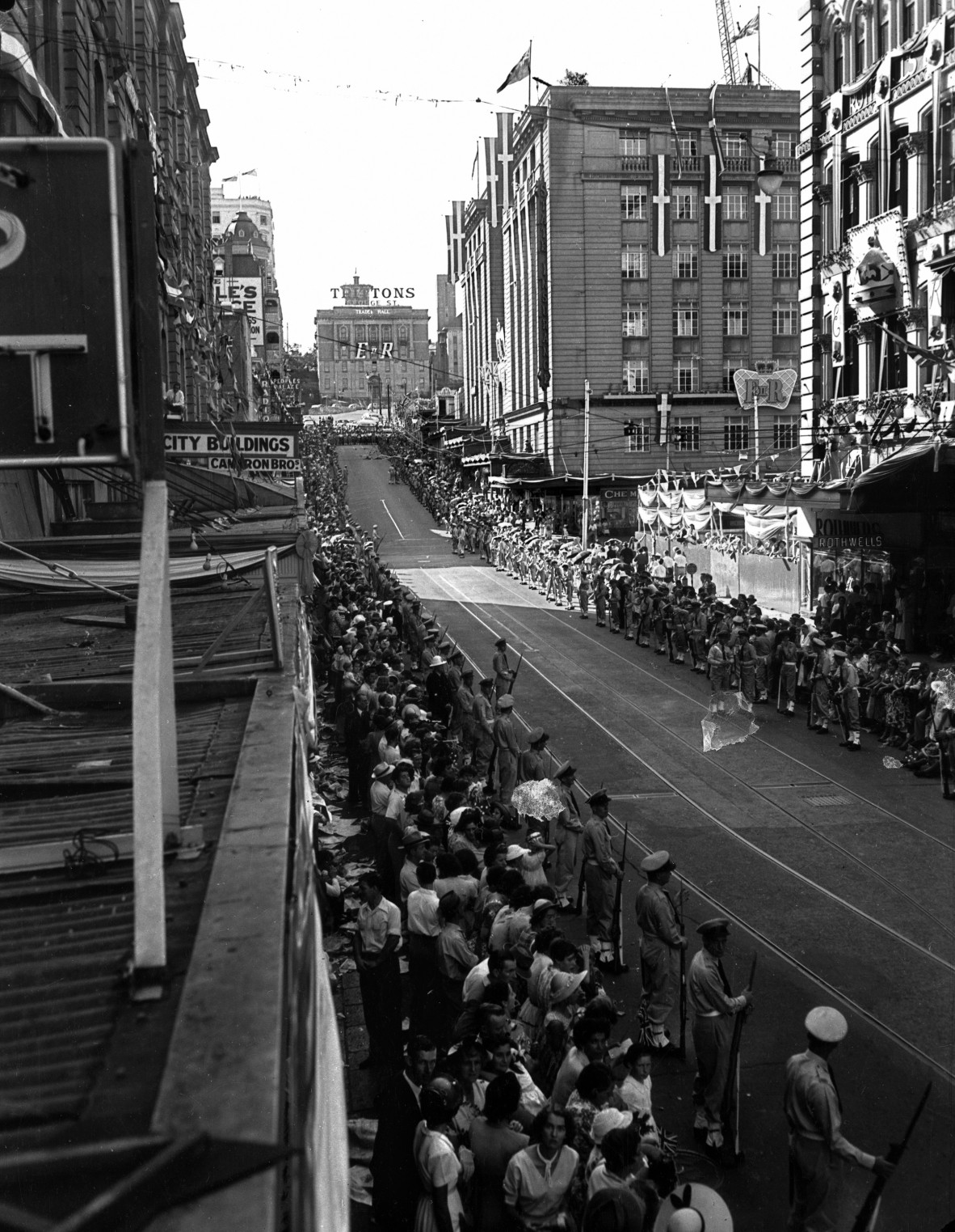 Black and white photograph of crowds lining Edward Street, Brisbane City for Royal Visit. Tritton's sign visible atop one of the buildings. 