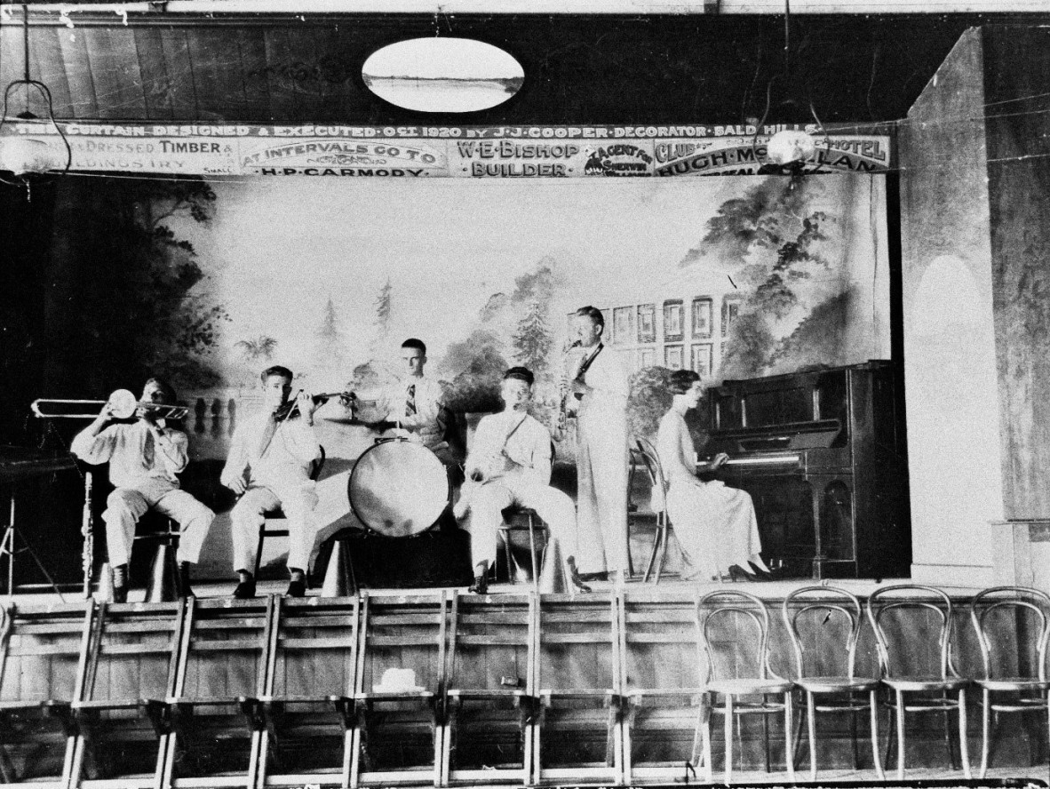Black and white image of six people playing instruments on a stage at Caboolture ca 1929