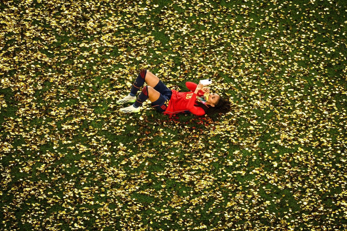 A photo of a Football player lying on her back on a field with confetti 