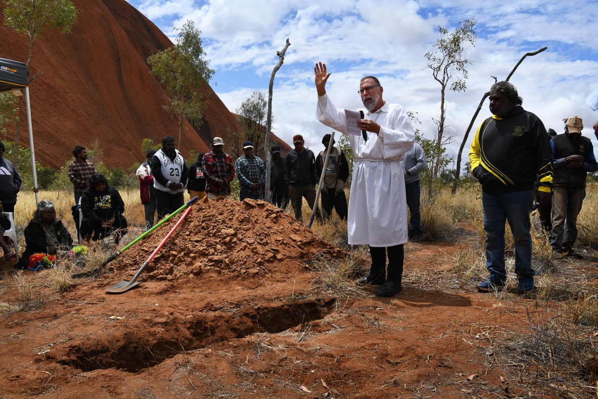 A photo of Aboriginal people gather for a burial ceremony with a pastor presiding