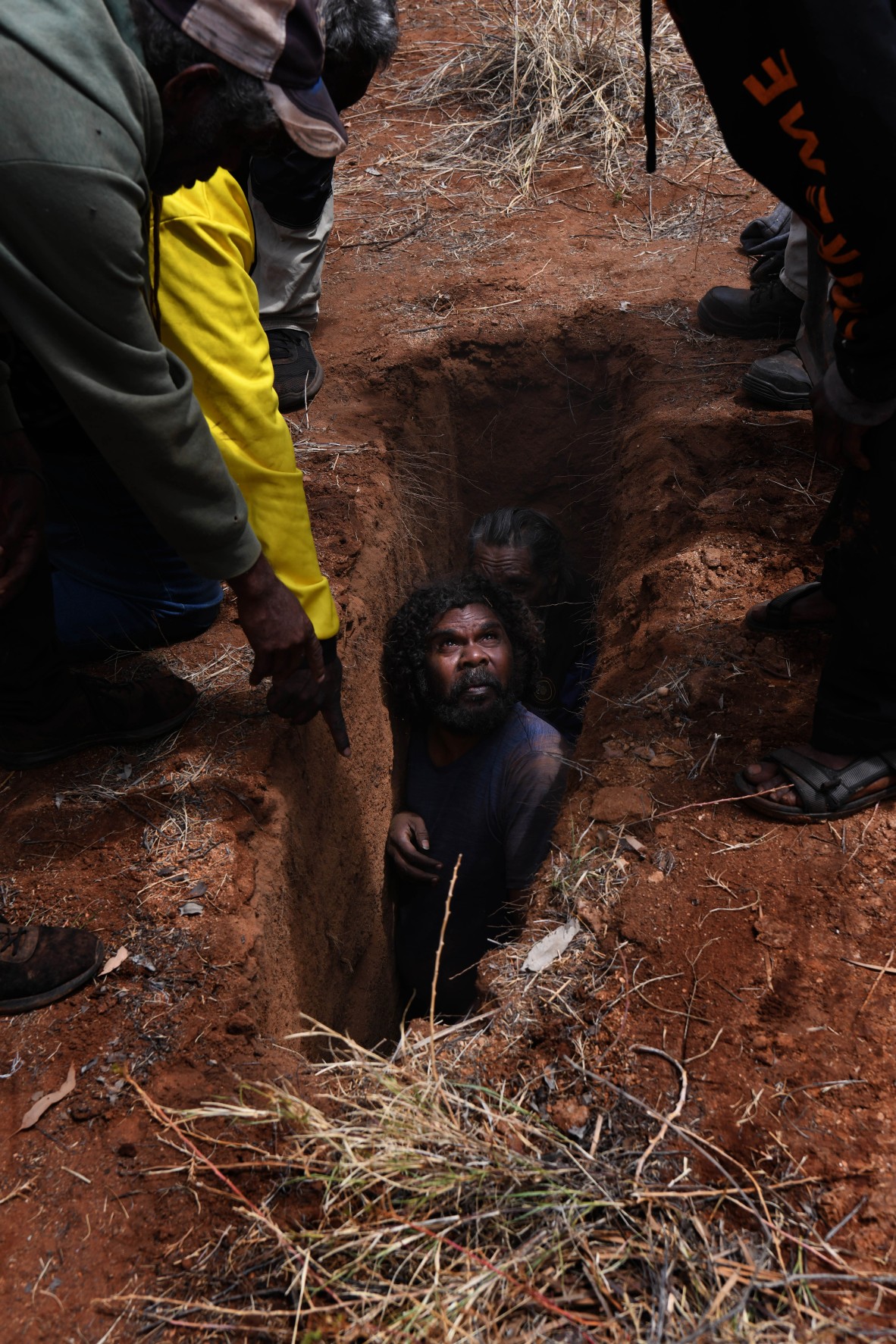 A photo of an Aboriginal man in a grave preparing for a burial