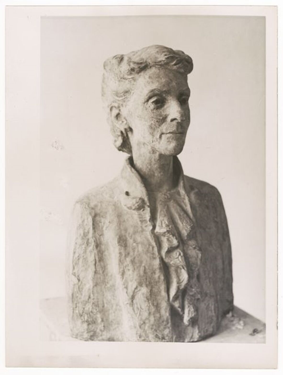 A sculpture of a woman wearing a blouse and with her hair pinned up