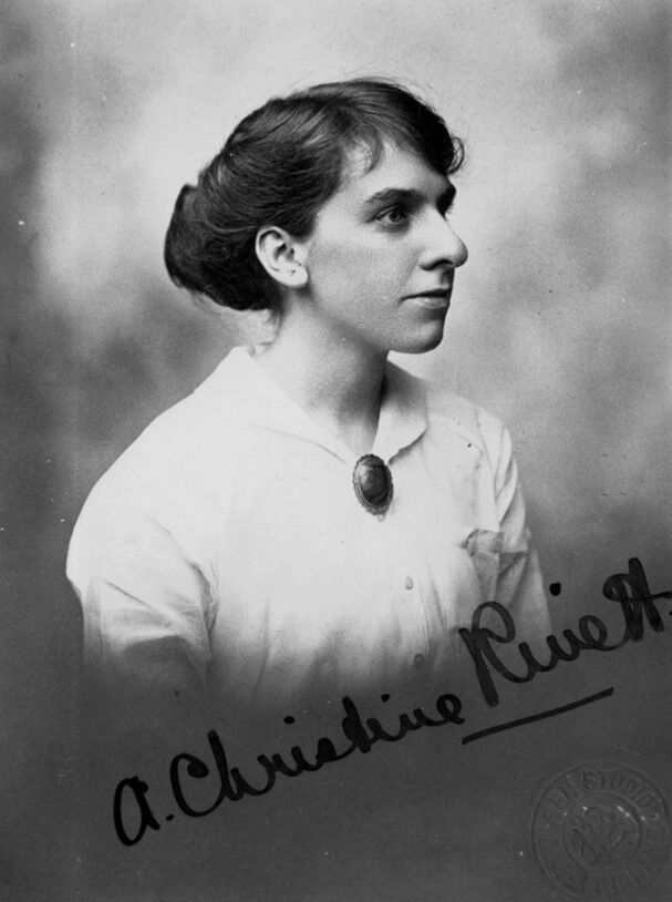 A side profile or a woman with her hair tied back wearing a light coloured blouse