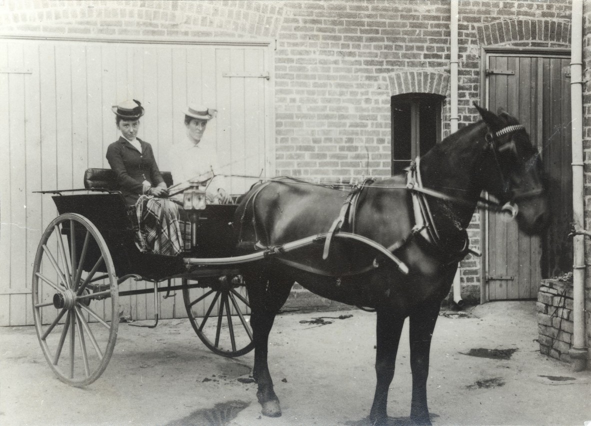 Black and white photograph from ca.1900, depicting two women sitting in a horse drawn buggy