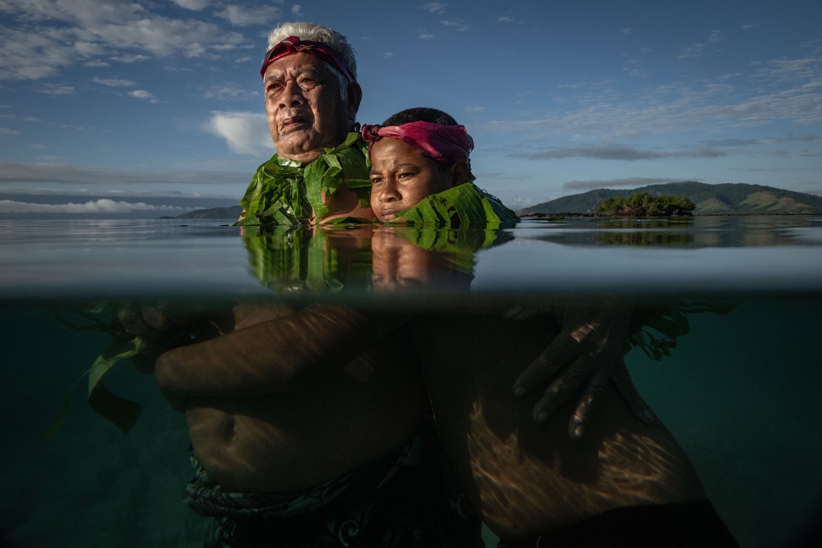 Photo of a man and child standing in water on the remote Kioa Island in Fiji