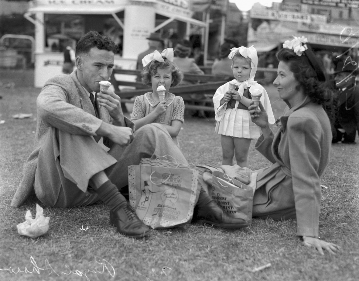 A family sitting on the grass at the Ekka enjoying an ice cream
