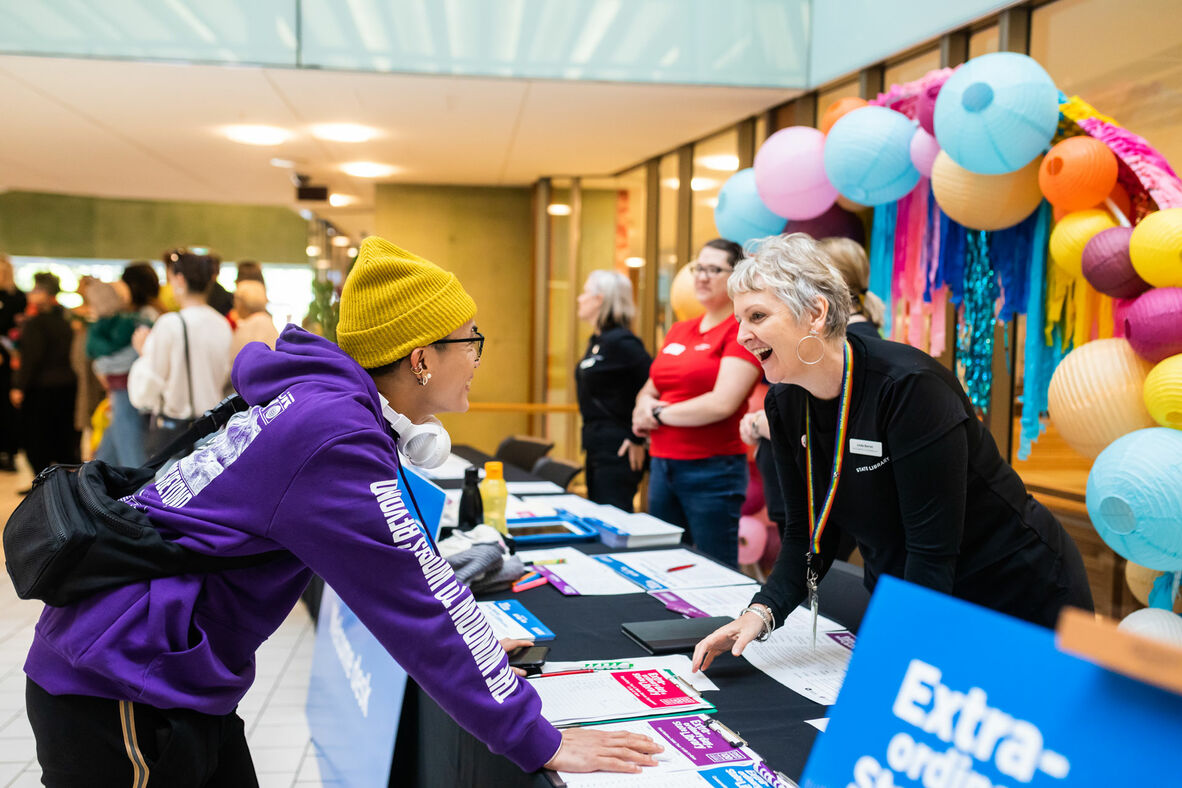 Visitor talking to happy staff member behind a desk during an event at State Library.