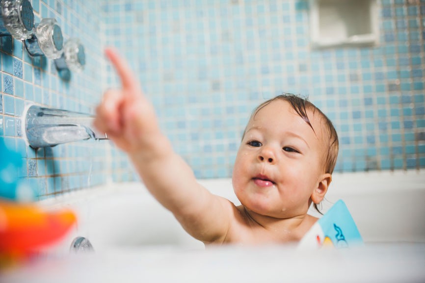 Baby in bath pointing finger