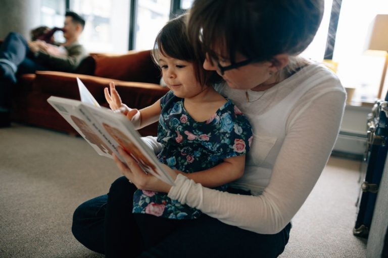 Mother and daughter on floor, reading a book