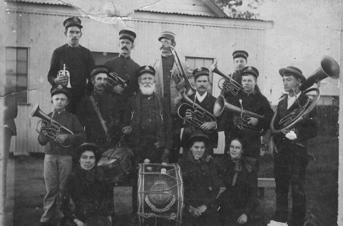 A black and white photograph of Salvation Army members holding brass instruments, and standing beside the Salvation Army barracks in Oak Street, Barcaldine in 1897