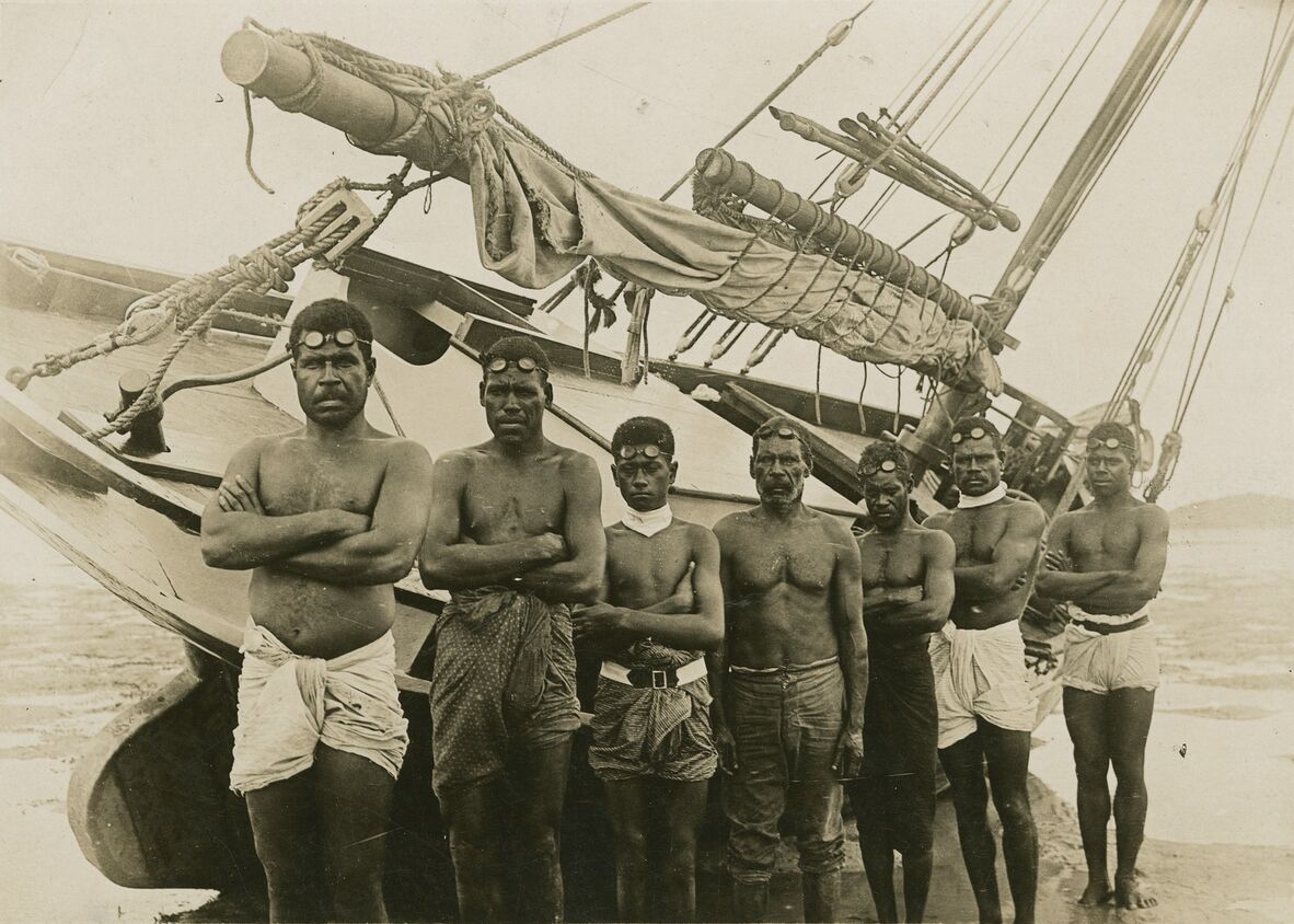 Pearl divers standing in front of their boat in the Torres Strait, 1920