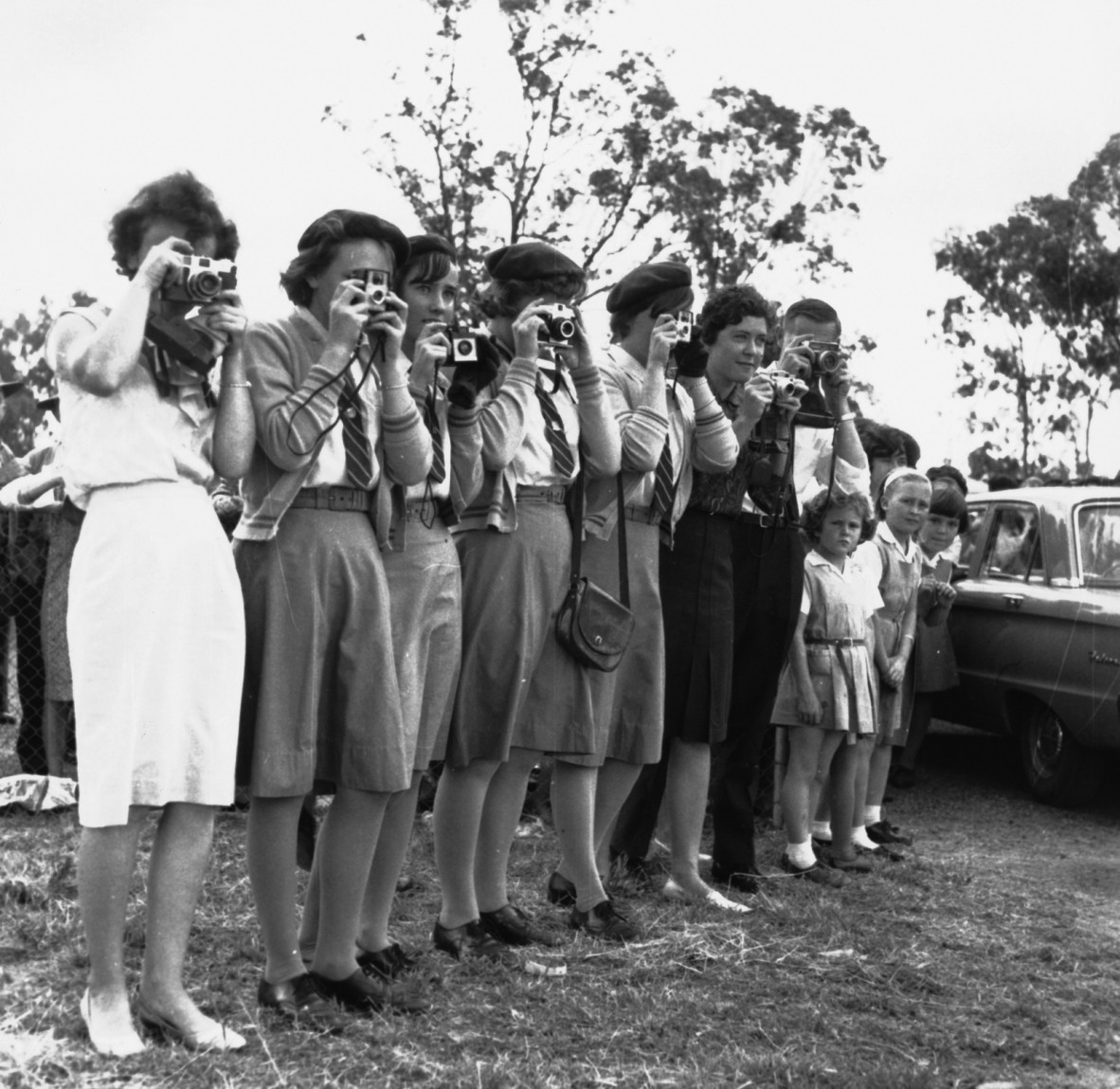 Excited schoolgirls line up with their cameras for a first glimpse of Prince Charles, Eidsvold, May 1966