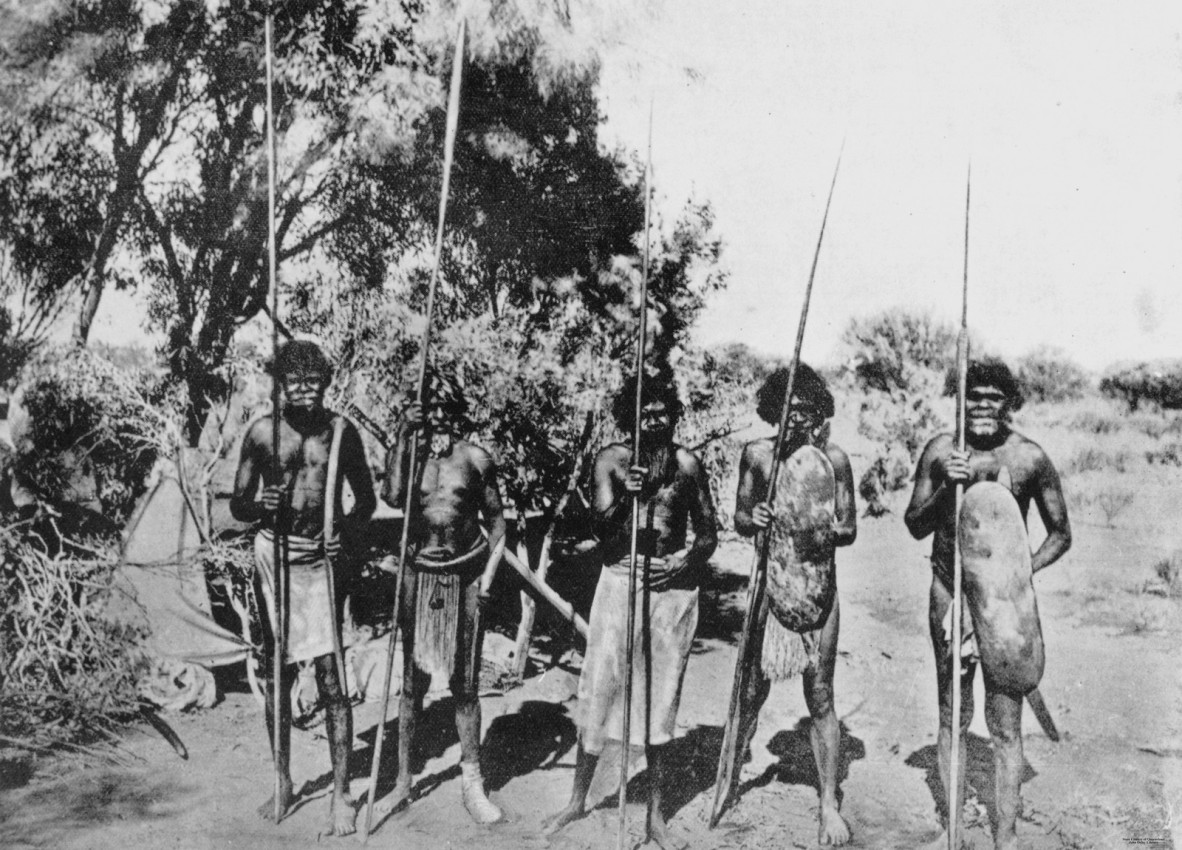 Group of men with spears and shields, standing in front of a shelter in the Thargomindah District, ca.1890.