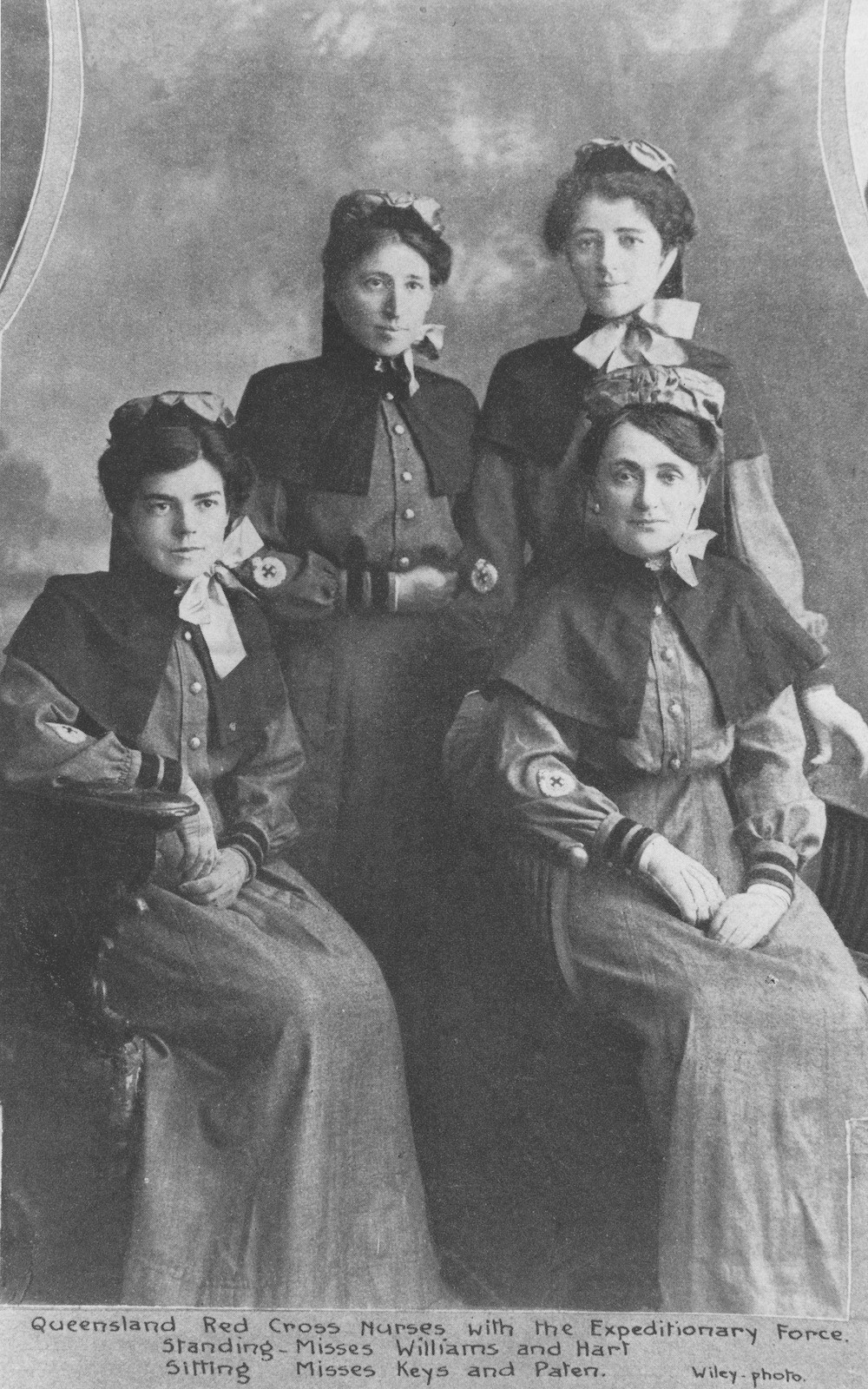 Studio group portrait of the first four Queensland nurses selected for the Australian Army Nursing Service. Identified: Standing left, Miss Williams; Miss Hart (right). Seated left to right, Miss Keys and Miss Paten.