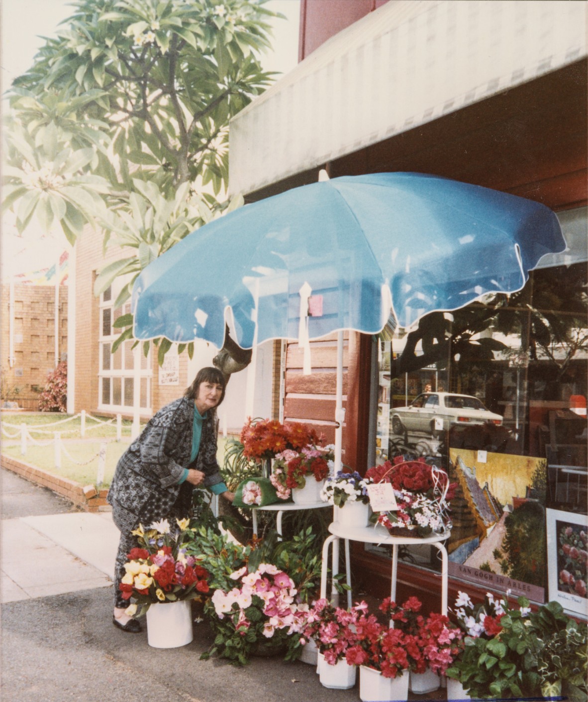 Joy de Gruchy in front of Craftsman's Market arranging a colourful display of flowers.