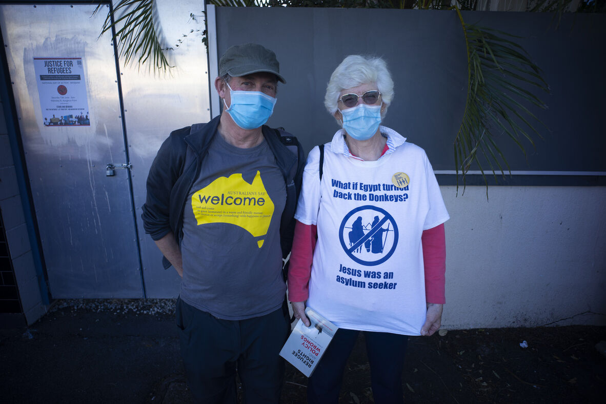 Couple wearing shirts advocating for refugee rights in front of Kangaroo Point Central Hotel & Apartments, Brisbane, 2020.