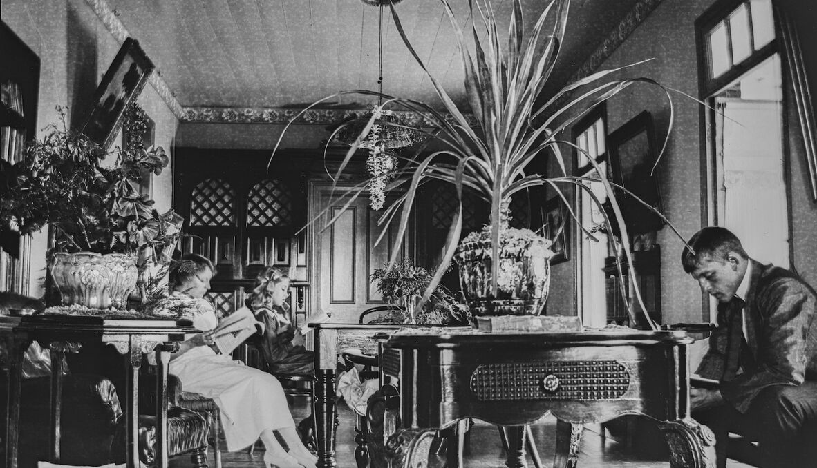 Eileen, Marjorie and Allan Row reading inside their home at the Dunwich Benevolent Asylum.
